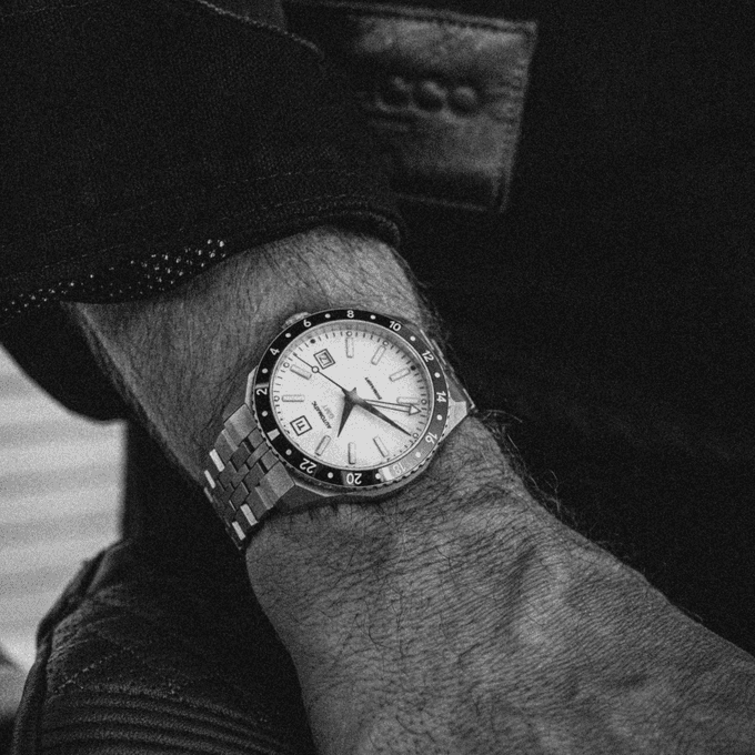 Big Idea Design LLC titanium GMT watch on wrist with silver bracelet white dial and 24 hour bezel