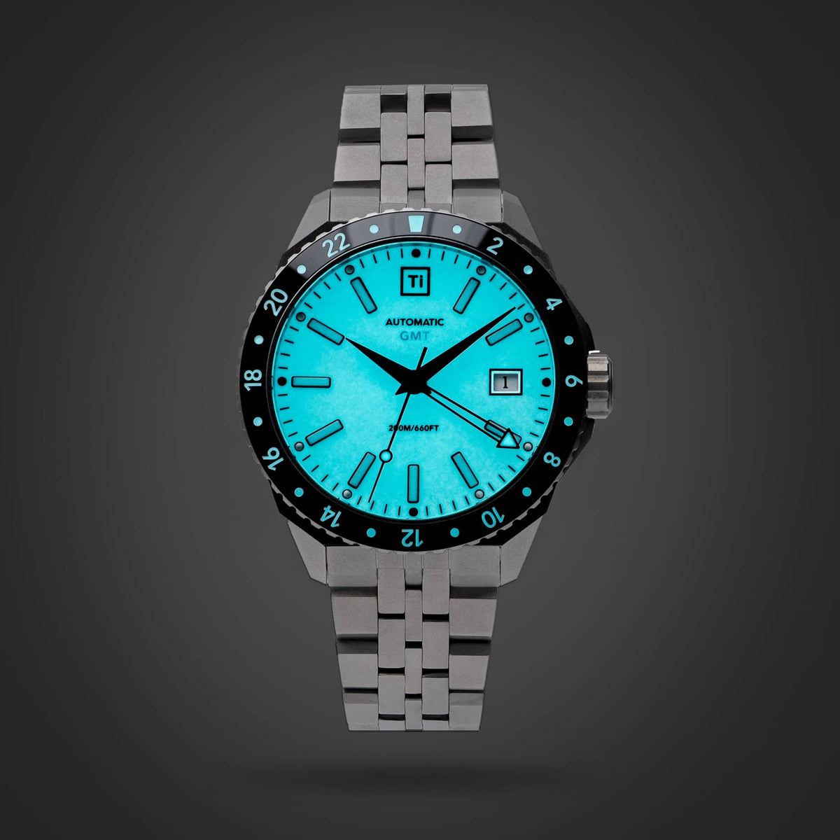 Big Idea Design LLC titanium GMT watch with glowing turquoise dial black 24 hour bezel and date window