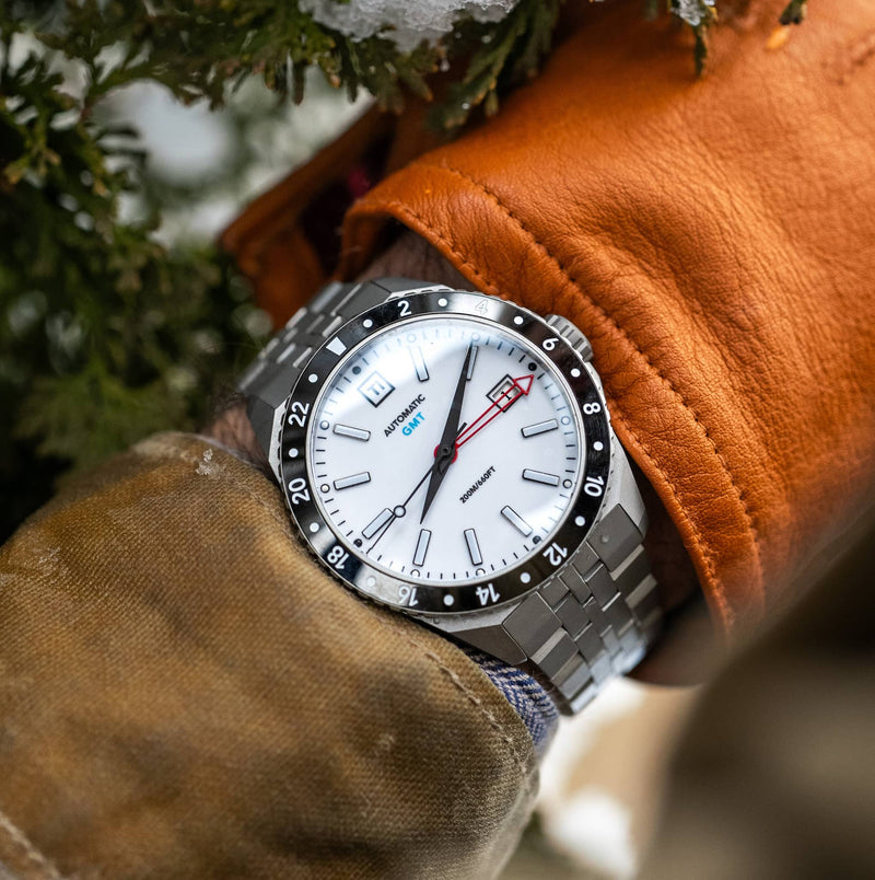 Big Idea Design LLC titanium GMT watch on wrist with white dial red GMT hand and bracelet in winter