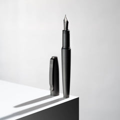 Big Idea Design LLC sleek black Titanium Fountain Pen with cap standing on white surface